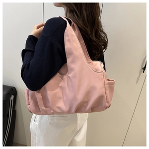 Dettaglio borsa tote rosa chiaro con tasca laterale e fondo a pieghe sulla spalla