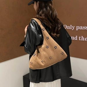 Brown suede tote bag with laser-cut floral patterns shown in a stylish street style view