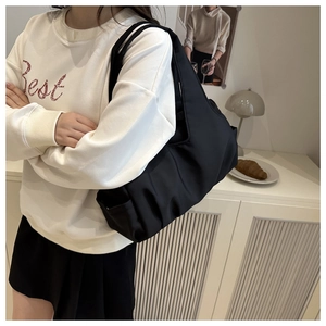 Dettaglio di una borsa tote in nylon nero trapuntato con pieghe e ampia tracolla morbida