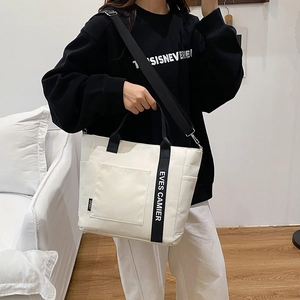 White canvas commuter tote bag with black handles and adjustable shoulder strap