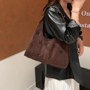 Brown suede underarm tote bag with floral cutouts shown on a female model shoulder