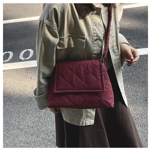 Detailansicht der weinroten Stepptasche mit Rautenmuster, von einem Modell getragen