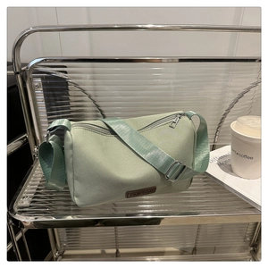 Vue détaillée du sac à bandoulière en toile vert clair avec étiquette en cuir