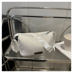 Détail du sac bandoulière blanc avec fermeture éclair argentée et étiquette FASHION