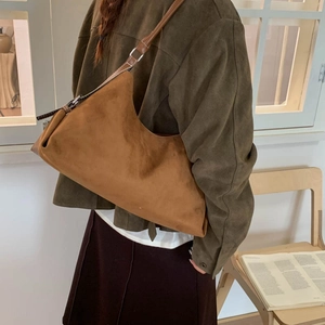 Sac hobo vintage en daim marron avec bandoulière en cuir dans un décor minimaliste