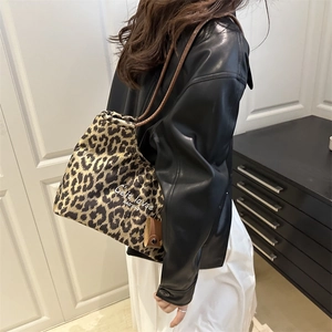 Women's leopard print tote bag with long brown handles shown in a modern interior setting