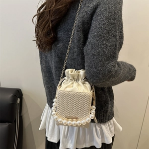 Elegant off-white woven bucket bag with pearl handle and gold chain shoulder strap