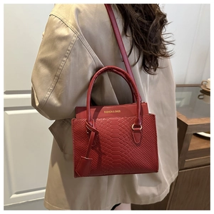 Detail of burgundy animal-patterned leather bag with gold logo and long shoulder strap