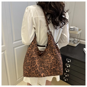 Detail view of large leopard print tote bag worn over the shoulder showing spacious hobo design
