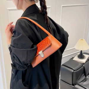 Orange croc-embossed shoulder bag for women styled with a chic black coat for autumn