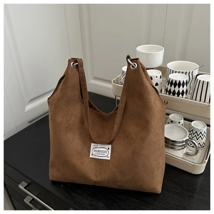 Detail of dark brown matte suede tote bag with stylish fabric label in a home setting