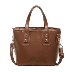 Brown glossy bucket bag with gold studs and adjustable strap on white background