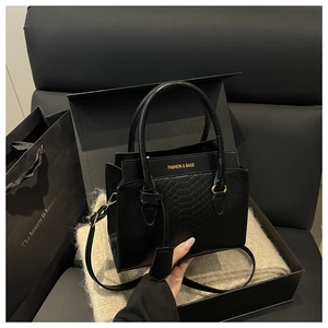 Detail of black embossed leather crossbody bag presented in a premium branded gift box