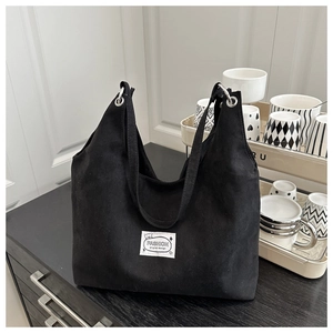 Detailed view of the black canvas tote bag with a white FASHION original design woven label