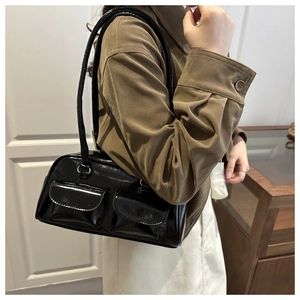 Detail of black patent leather Boston bag featuring dual front flap pockets and slim straps