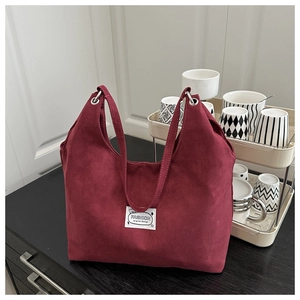 Macro detail of wine red suede tote bag with metallic ring and white fabric label