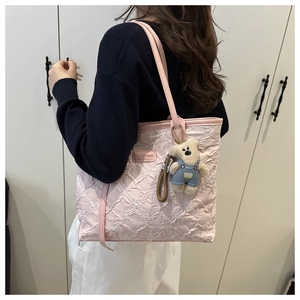Dettaglio borsa tote trapuntata rosa con tracolla in pelle e charm orsetto