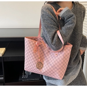 Detailed view of the light pink tote bag featuring a metallic M pendant and logo print