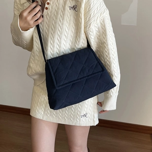 Dunkelblaue Stepptasche mit Rautenmuster, Klappe und schmalem Schultergurt an einem Model