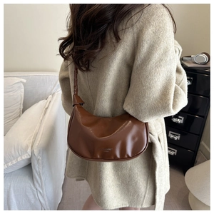 Sac croissant en cuir marron avec bandoulière nouée porté sur un manteau de laine beige