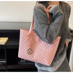 Pink tote bag detail with M-letter monogram print and golden metal charm on strap