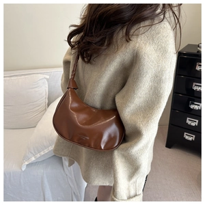 Brown half-moon underarm bag with twisted strap and polished leather detail