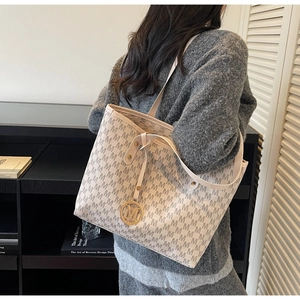 Detail of a large cream tote bag with grey M-monogram print and gold charm for work