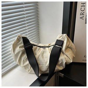 Close-up of beige textured nylon bag with black shoulder strap and zipper detail