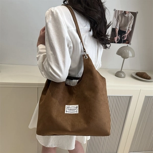 Brown large capacity tote bag in matte faux suede shown on shoulder for daily commute