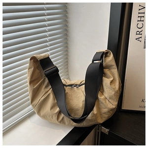 Detail of khaki crescent crossbody bag with nylon texture and double zippers