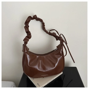 Detail of dark brown faux leather hobo bag with pleated handle and side ribbon detail