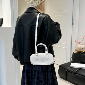 Minimalist white leather crossbody bag with top handles and gold hardware on female model