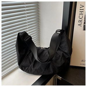 Close-up of black nylon half-moon bag with pleated texture and silver zipper detail