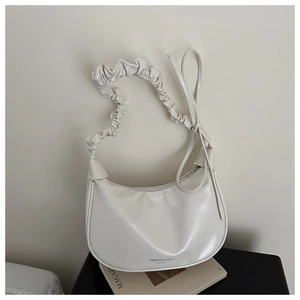 Detail of cream half-moon bag featuring a unique cloud pleated handle and smooth PU leather