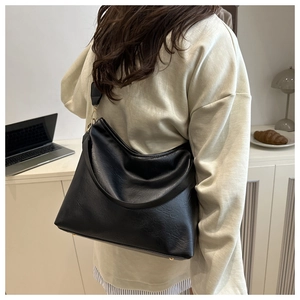 Détail d'un grand sac cabas noir en similicuir texturé porté en bandoulière par un mannequin