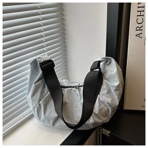 Detail of light blue-grey nylon dumpling bag with adjustable wide black strap