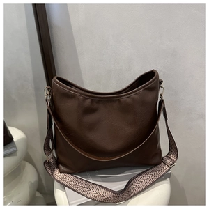 Détail du sac cabas en cuir marron foncé avec bandoulière tissée et texture de surface riche