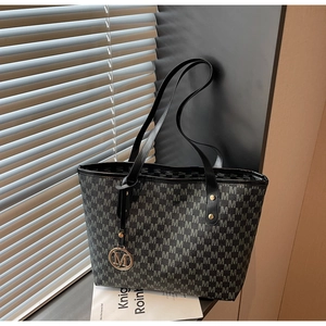 Detail of large tote bag with M-letter pattern print and gold metal logo pendant