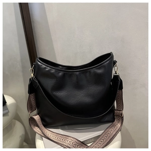 Détail du sac hobo noir avec une bandoulière tissée géométrique et des boucles dorées