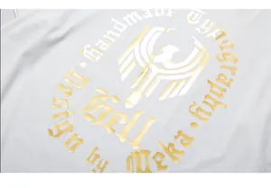 Detail of golden foil print and eagle logo on white street-style oversized T-shirt