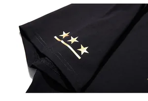 Detailed close-up of golden stars printed on the sleeve cuff of a black cotton t-shirt