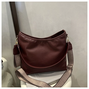 Détail d'un sac cabas bordeaux avec bandoulière bohème tissée et boucles dorées