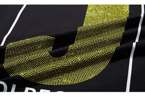 Vue macro détaillée des strass jaunes et de la typographie blanche sur un t-shirt noir