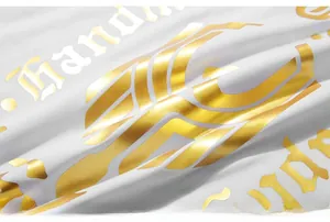 Close-up of golden handmade lettering and geometric prints on white fabric surface