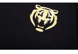 Gros plan du motif tigre doré et texte Panda Remix sur le tissu en coton noir du T-shirt