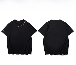 Detail of gold handwritten embroidery on the collar and sleeve of a black cotton t-shirt