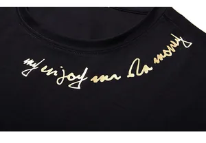 Detail view of round neckline and golden foil script print on a black cotton t-shirt