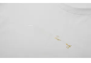 Macro detail of crew neck collar and golden calligraphy print on white cotton T-shirt