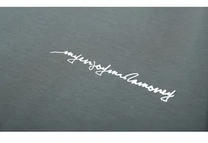Gros plan d'une broderie cursive blanche sur un t-shirt en maille gris anthracite ample