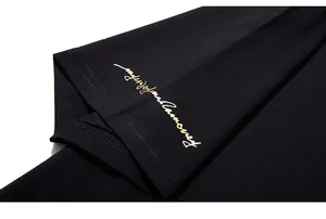 Detailed macro shot of gold script embroidery on the black T-shirt sleeve cuff